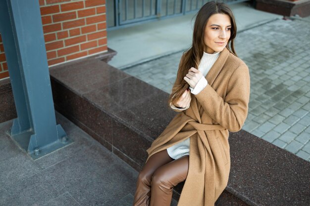 Pretty woman in trendy clothes sitting outdoors