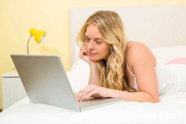 Pretty woman using laptop in her bed