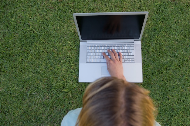 Pretty woman using laptop in park