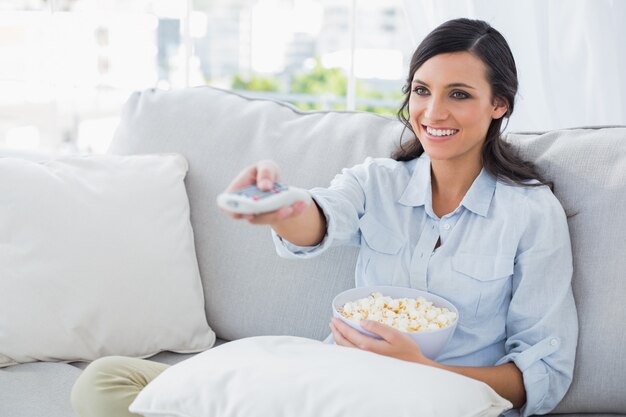 Donna graziosa che guarda tv che mangia popcorn