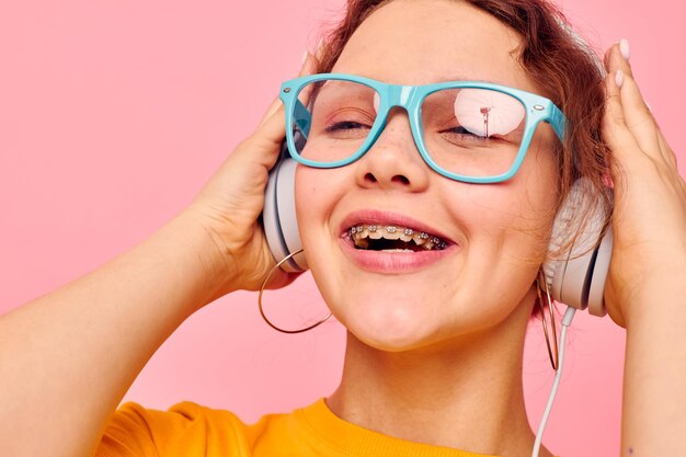 Pretty woman wearing blue glasses listening to music on headphones isolated backgrounds unaltered