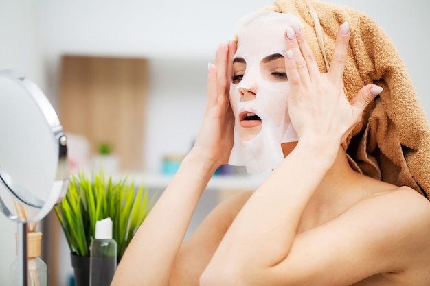 Pretty woman wearing face care mask at home