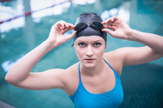 Красивая женщина носить шапочку для плавания и очки для плавания в бассейне