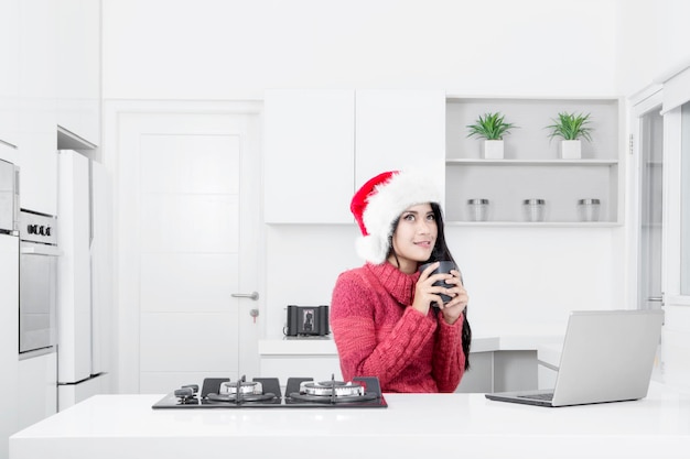 Pretty woman wears Santa hat in the kitchen