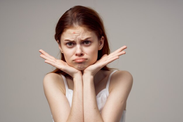 Pretty woman in a white tshirt pimples on the face light\
background