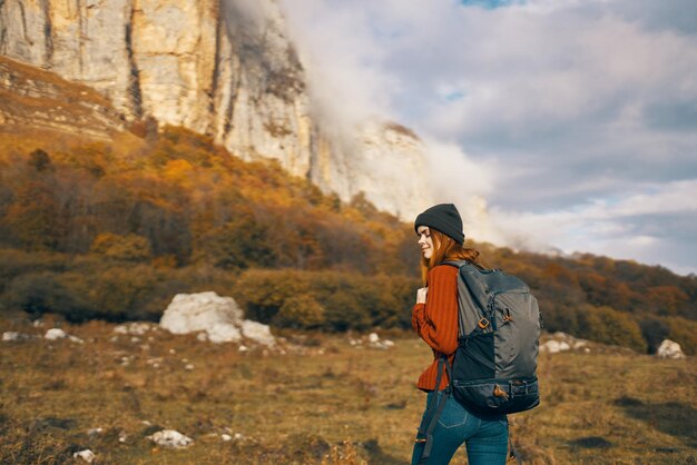 Pretty woman with a backpack in the fall in the mountains jeans hat leisure relax