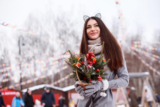 Pretty woman with cat ears headband is spending time outdoors at christmas fair winter holidays