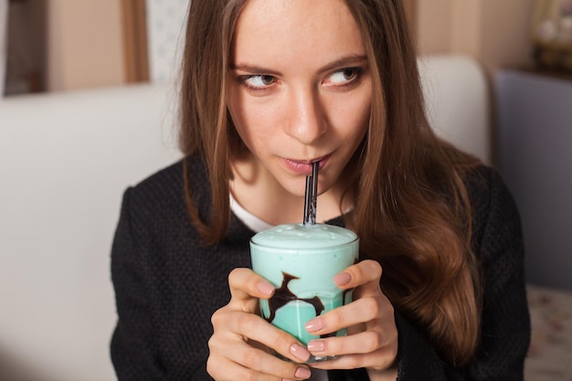 Pretty woman with cocktail in modern cafe