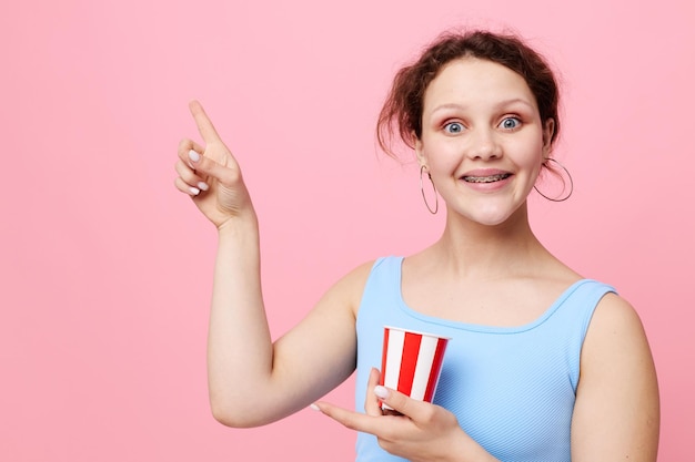 Pretty woman with disposable glass posing pink background