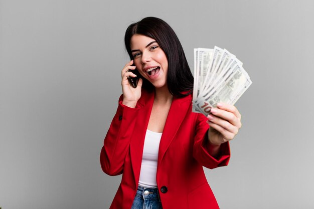 Pretty woman with dollar banknotes and using her\
smartphone