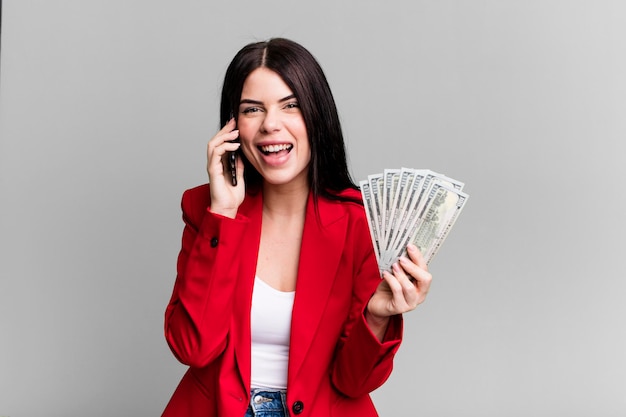 Pretty woman with dollar banknotes and using her\
smartphone