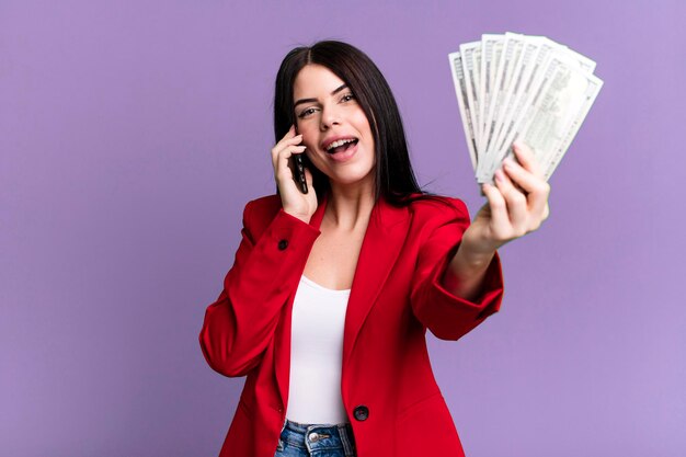 Pretty woman with dollar banknotes and using her\
smartphone