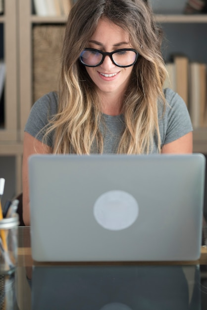 Pretty woman with glasses eyewear work at home on laptop\
computer - smart working female people at office desk looking the\
monitor - professional modern job freelance lifestyle concept