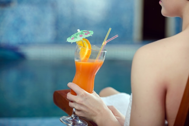 Pretty woman with juice by the pool.