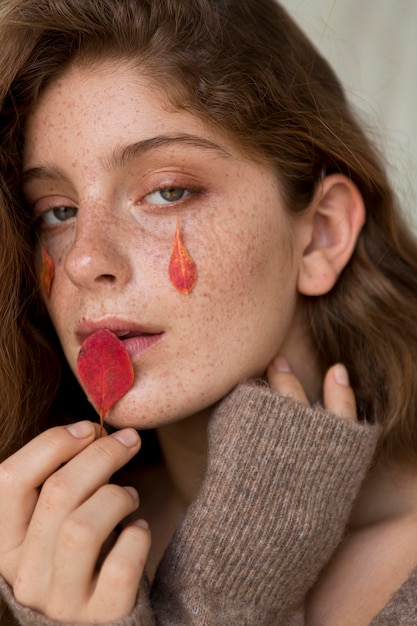 Foto bella donna con foglie sul viso