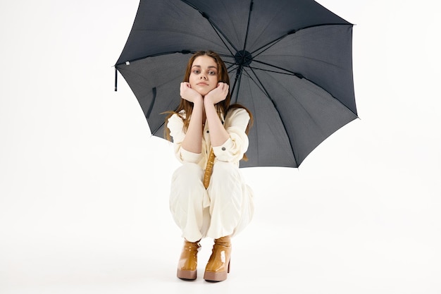 Pretty woman with open umbrella squatting fashion studio High quality photo