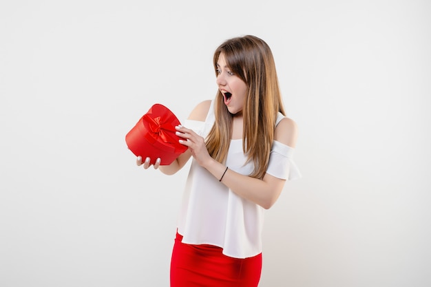 Donna graziosa con il contenitore di regalo del biglietto di s. valentino a forma di cuore rosso isolato