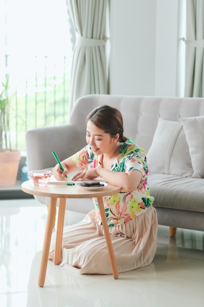 Красивая женщина пишет возле дивана дома в гостиной
