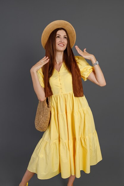 Pretty woman in yellow dress standing in studio