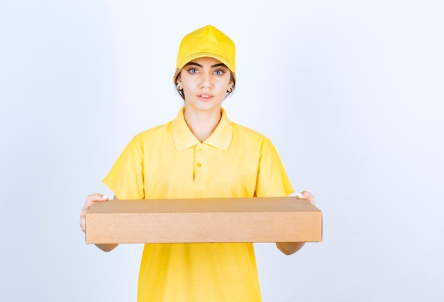 A pretty woman in yellow uniform holding a brown blank craft paper box .