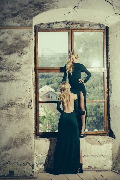 Pretty women in green dresses near window