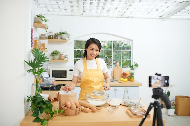 꽤 젊은 아시아 여성 음식 블로거가 새로운 비디오를 만들고 요리하는 방법을 설명합니다