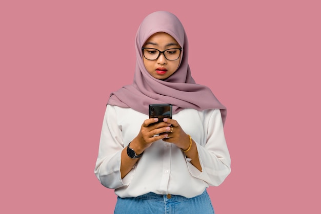 Pretty young asian woman feeling confused and holding smartphone