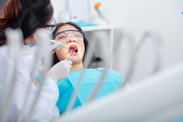 Pretty young Asian woman getting her teeth treated in dental clinic