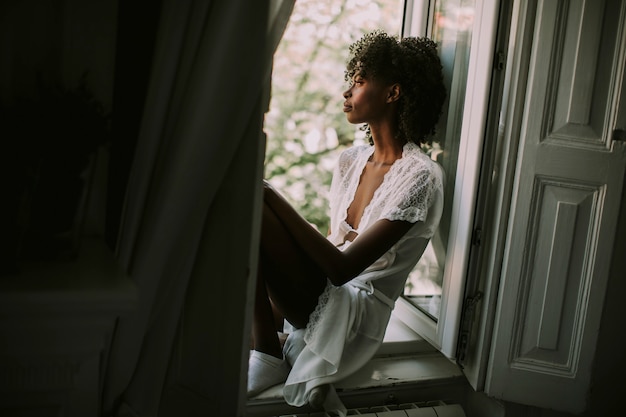 Pretty young black woman sitting on the window