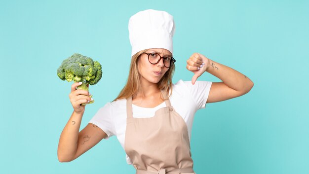 Donna chef bionda abbastanza giovane che tiene un broccolo