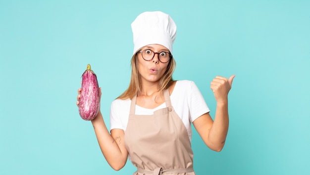 Pretty young blonde chef woman holding an eggplant