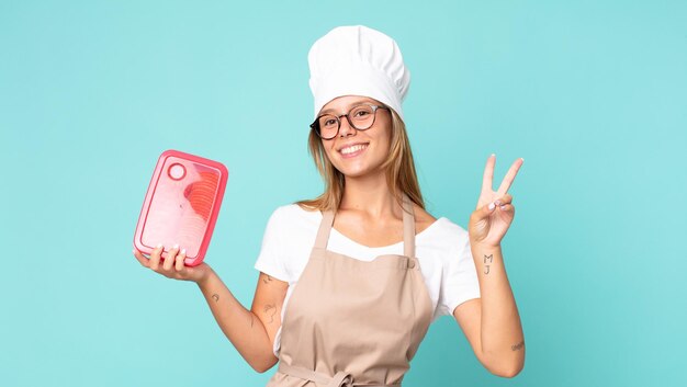 Donna chef bionda abbastanza giovane e con in mano un tupperware