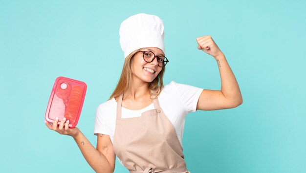 Donna chef bionda abbastanza giovane e con in mano un tupperware