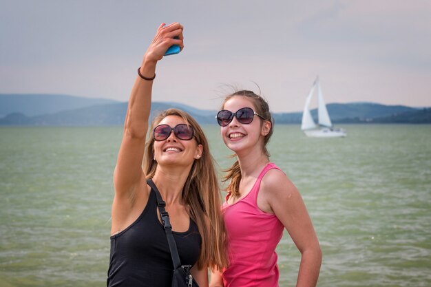 Pretty young blonde girls take a photo with mobile