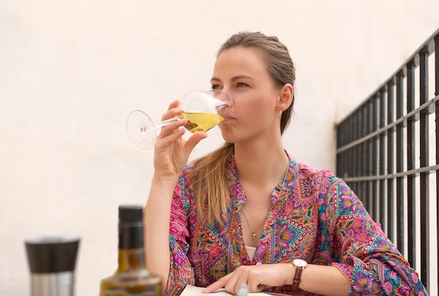 Pretty young blonde tasting a glass of wine on terrace