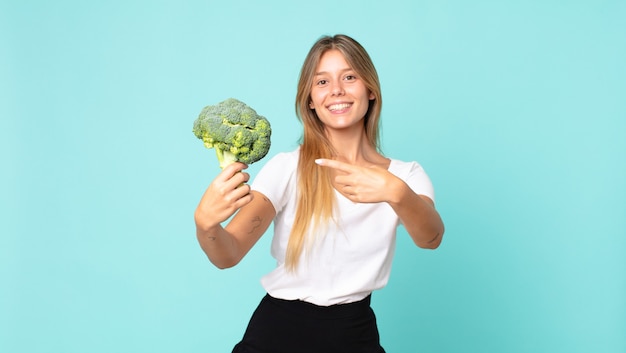 Donna bionda abbastanza giovane che tiene un broccolo