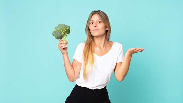 Pretty young blonde woman holding a broccoli