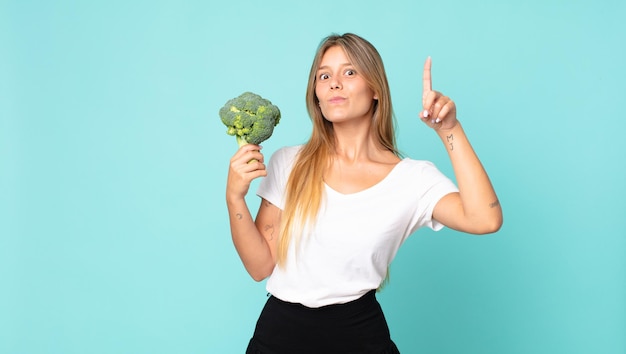 Donna bionda abbastanza giovane che tiene un broccolo