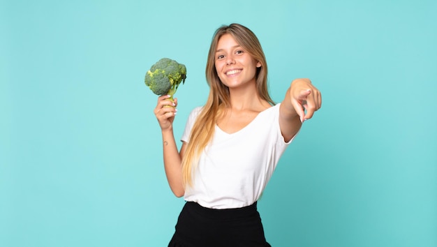 Pretty young blonde woman holding a broccoli