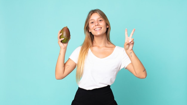 Pretty young blonde woman holding a mango