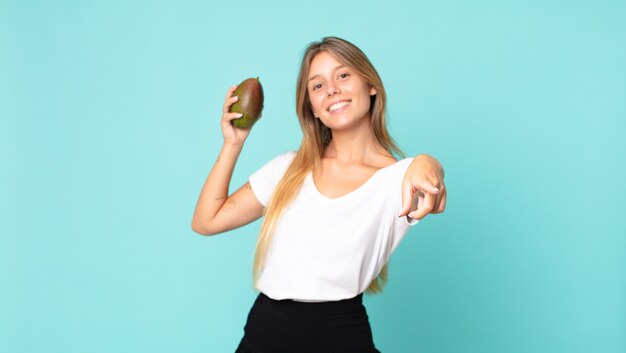 Pretty young blonde woman holding a mango