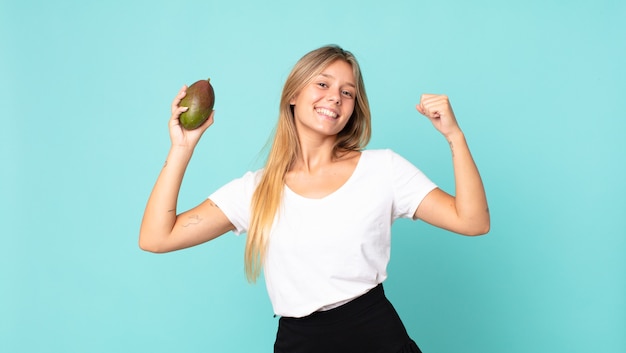 Pretty young blonde woman holding a mango