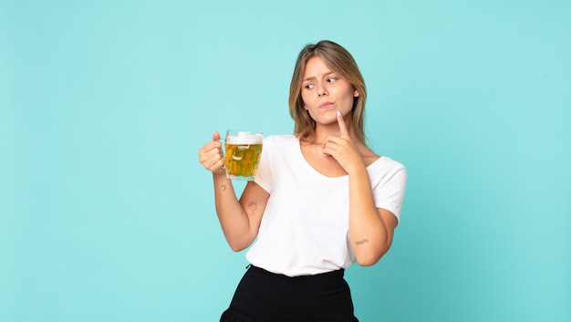 Pretty young blonde woman holding a pint of beer