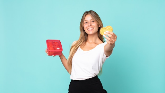 Pretty young blonde woman holding a tupperware