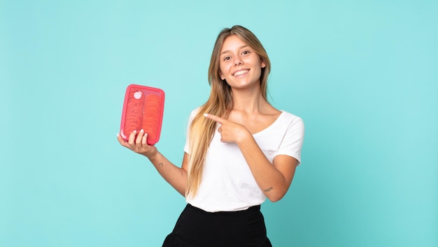 Pretty young blonde woman holding a tupperware