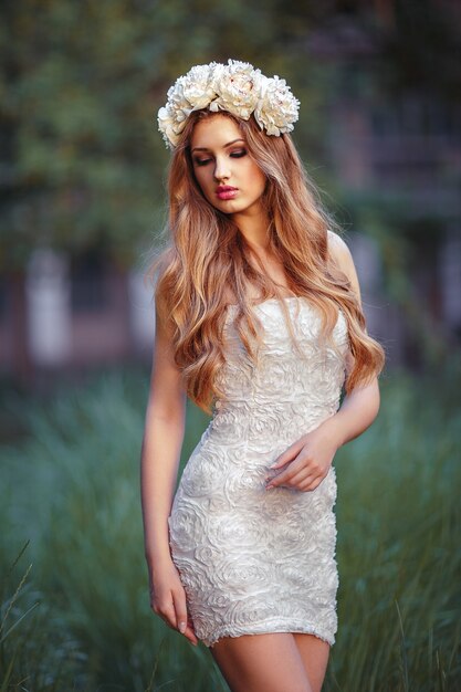 A pretty young blonde woman in summer dress in nature