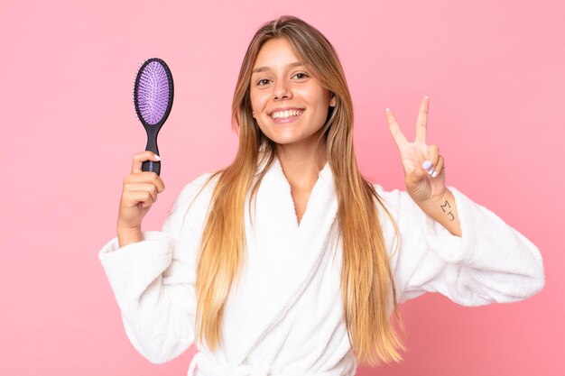 バスローブを着て、ヘアブラシを持っているかなり若いブロンドの女性