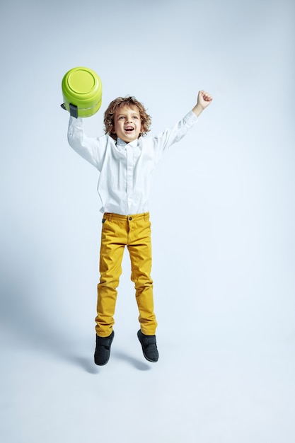 Pretty young boy in casual clothes on white wall