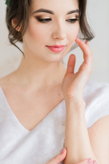 Pretty young brunette bride in an elegant wedding dress and hair-style in hotel in luxury interior.