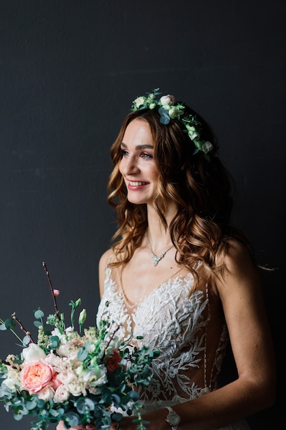 Pretty young brunette bride in an elegant wedding dress and hair-style in hotel in luxury interior.